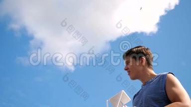年轻男子控制无人机在现场缓慢运动。 无人机操作员在美丽的天空背景上拿着发射机
